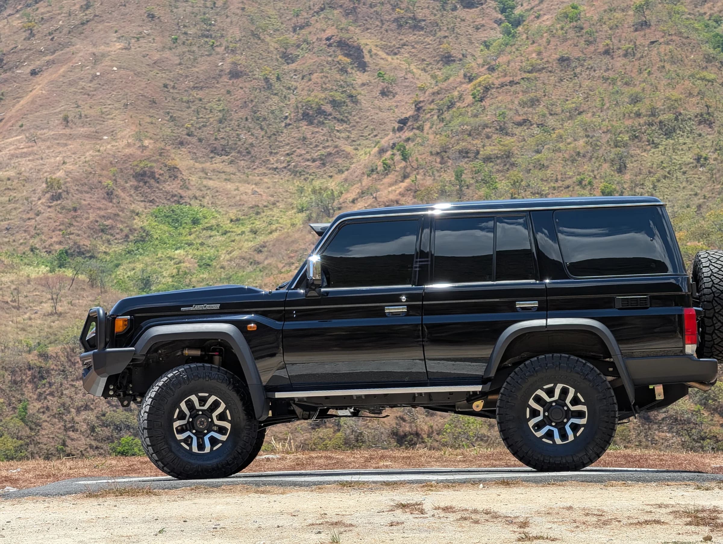 Toyota Hilux negra, vista lateral en terreno