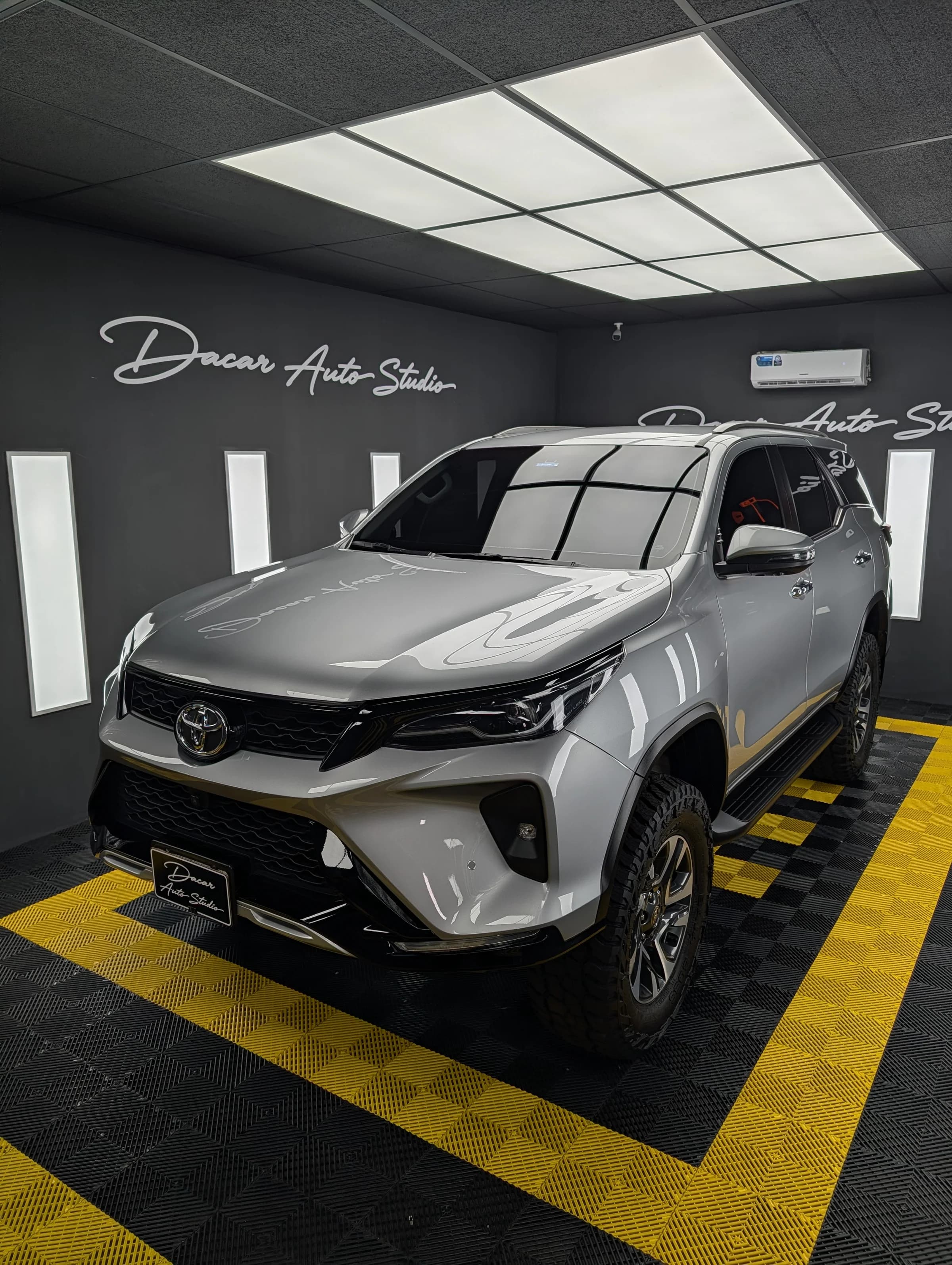 Cabina del Dacar Auto Studio con un Toyota Fortuner plateado en el área de trabajo